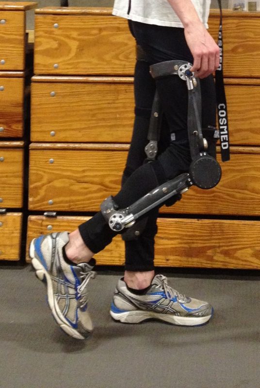 An individual mid-step assisted by a piston like knee apparatus