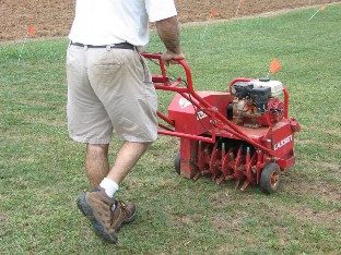 A core aerator (plugger) is being used to prepare an existing site for introduction of new grass seed.