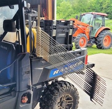 A four-wheeler with a cordless drill attached. The drill features an extra-long bolt-type bit used to roll poly wire onto a reel.